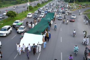 People having huge national flag marching on Islamabad Expressway to celebrate the Independence Day of Pakistan