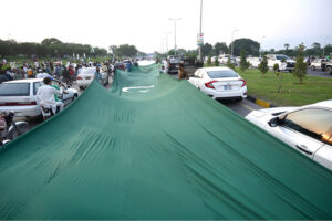 People having huge national flag marching on Islamabad Expressway to celebrate the Independence Day of Pakistan