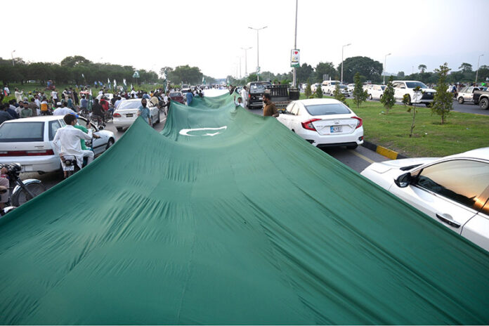 People having huge national flag marching on Islamabad Expressway to celebrate the Independence Day of Pakistan