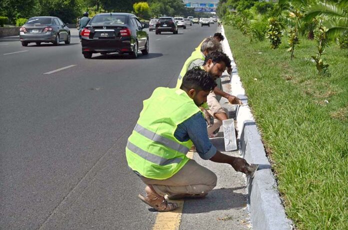 Workers busy repairing cemented blocks at center path of Islamabad Highway