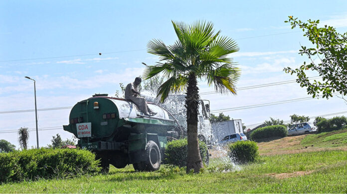 CDA worker watering plants to maintain the green belt ,keep the city green at Faizabad Interchange