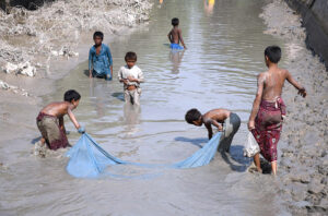Children busy in fishing in traditional way at a canal near new bas stand.