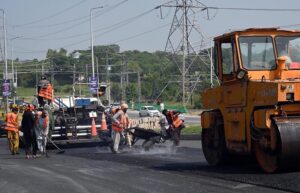 Labourers busy in road construction with the help of heavy machinery during development work near Faizabad.