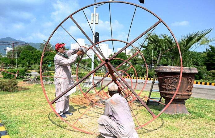 CDA workers busy fixing a tree stand to enhance beauty of Federal Capital in front of Parliament House