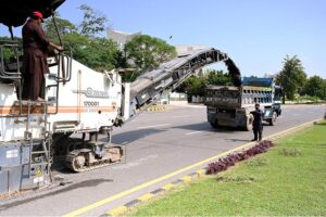 Labourers busy in road construction with the help of heavy machinery at Federal Capital