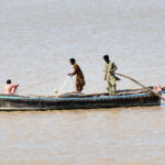 Fishermen busy fishing on their boat after the water level of the Indus River rises