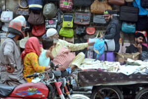 A motorcyclist selecting school bag for his kids from a roadside vendor