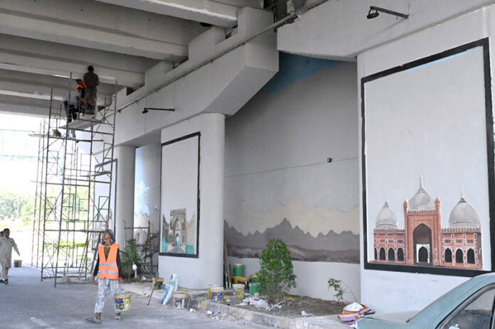 Workers painting the wall of 6th avenue underpass in the Federal Capital