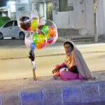 A woman vendor waiting for customers to sell balloons while sitting on the footpath at Latifabad