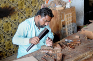 A skilled worker carving designs on the furniture wood at his workplace.