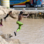 Children enjoying bath in the rain water accumulated in water pond in the Federal Capital