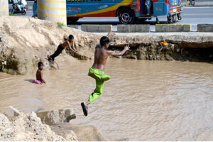 Children enjoying bath in the rain water accumulated in water pond in the Federal Capital