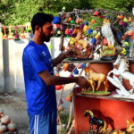 A vendor arranging and displaying the different kinds of clay made decoration items to attract the customers at his roadside setup