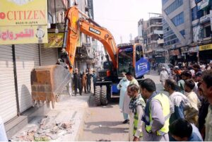 Tehsil Municipal Authority (TMA) workers clear illegal encroachments in Katchery Bazar using heavy machinery, ensuring smoother access for the public in the city.