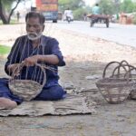 A worker is busy making baskets with the dry branches of a tree at roadside setup
