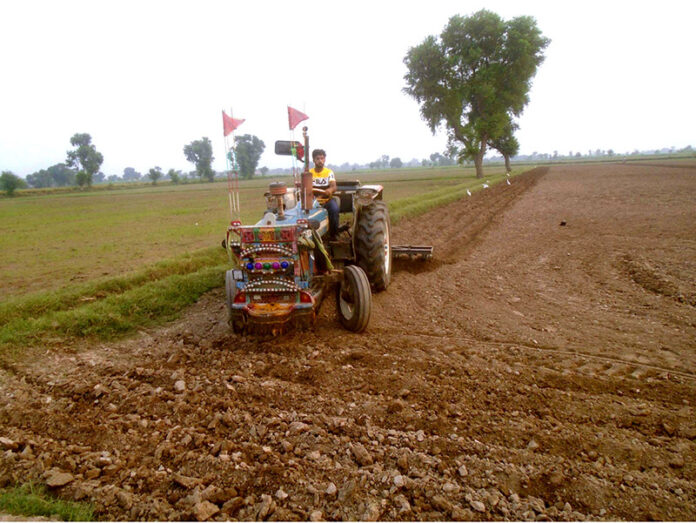 A farmer ploughing a farm field to prepare for new crop at Lahore Road