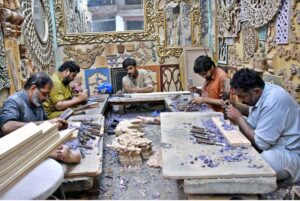 Workers are busy in preparing beautiful wooden mirror frames at their workplace.