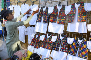 A vendor displaying colorful traditional children’s dress to attract the customers at Minara Road.