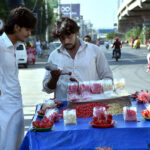 A vendor sells fresh pomegranates at the roadside, attracting customers