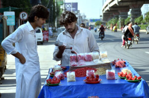 A vendor sells fresh pomegranates at the roadside, attracting customers