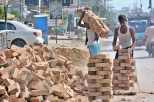 Labourers busy shifting bricks during construction work of a house at Latifabad.