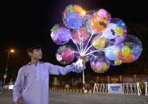 A strolling vendor selling illuminated balloons, brightening the streets to attract the customers as he strives to earn his livelihood at Kheam Chowk.