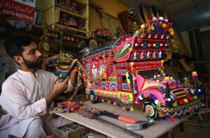A skilled craftsman applies the final touches to a vibrant, handmade traditional truck at his workshop near the Dabgari area in the Provincial City