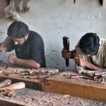 Workers are busy carving designs on wooden sheets at their workplace