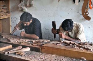 Workers are busy carving designs on wooden sheets at their workplace