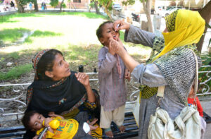 Lady health worker administers polio drops at Sindh Government Paretabad Hospital, part of Polio-Free Pakistan campaign.