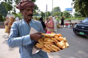 A street vendor selling delicious traditional 'Samosas' on a plate at Company Bagh, inviting to visitors for a local snack.