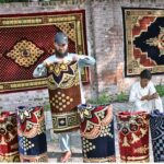 Vendor is busy in displaying traditional carpet to attract customers at his roadside setup