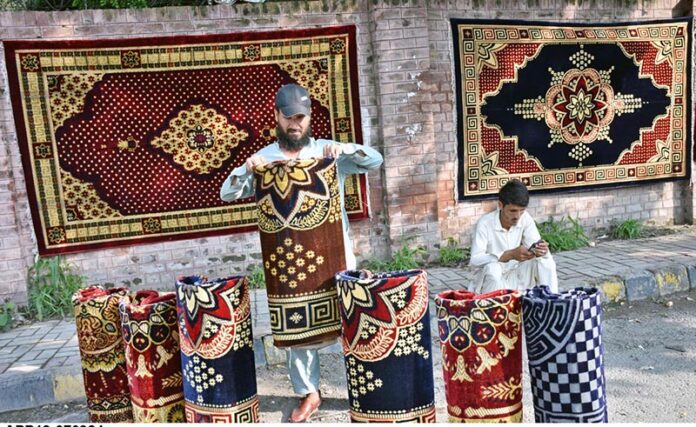 Vendor is busy in displaying traditional carpet to attract customers at his roadside setup