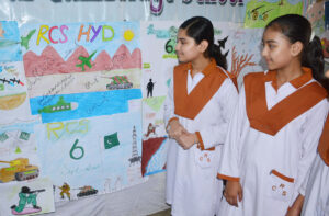 Girl students taking interest in drawing on Defense Day paintings exhibition at a local private school.