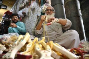An elderly man meticulously crafts slingshots at his workshop for sale near Dabgari area.