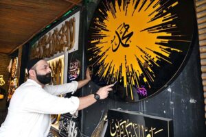 An artist creates beautiful calligraphy in a plastic signboard (Arashi Katbah) in preparation for Eid Milad-ul-Nabi (PBUH) celebrations at Samanabad LOS Road