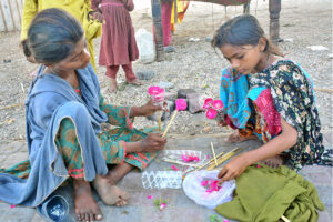 Gypsy girls girls preparing the flowers bouquets for selling of customers outside road at Qasimabad.