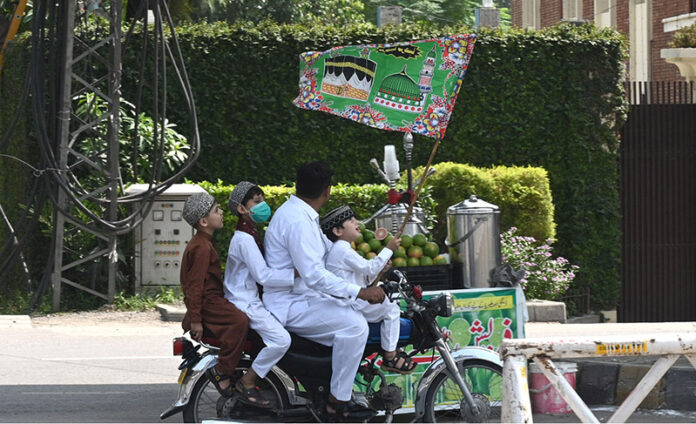 A family on motorcycle attending the religious procession of Eid Milad-un-Nabi celebrations in the city