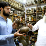 An antiques dealer shows a timeless treasure to an eager customer at Afghan market Sarafa bazar