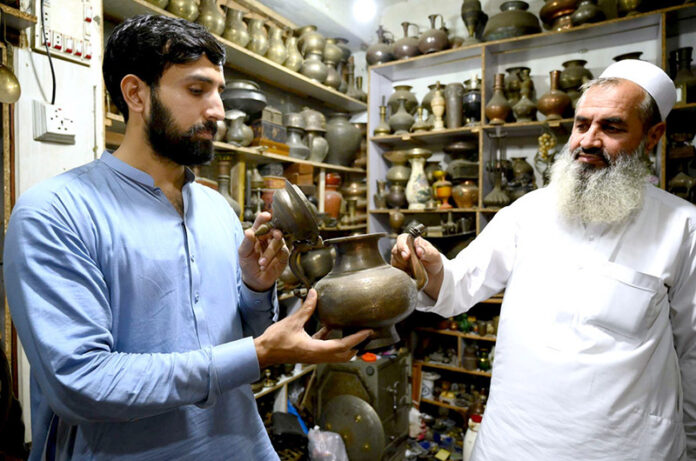 An antiques dealer shows a timeless treasure to an eager customer at Afghan market Sarafa bazar