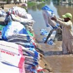 Labourers busy washing empty plastic bags in the canal