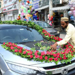 A worker decorates a vehicle with fresh flowers for a wedding ceremony in the city