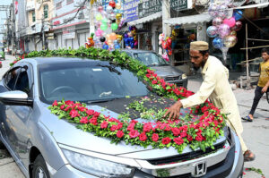 A worker decorates a vehicle with fresh flowers for a wedding ceremony in the city