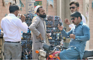 A motorcyclist selecting and purchasing sunglasses from a roadside vendor