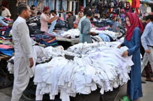 Women selecting and purchasing second-hand shirts at flea Market in provincial city
