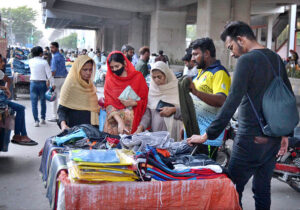 People busy buying second-hand, affordable trousers and shirts from a vendor near the Orange Train Flyover .