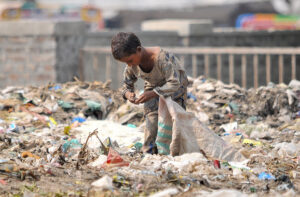 Gypsy girl searching valuables from the heap of garbage to earn bread and butter for her family.