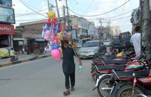 A young vendor wanders the streets of Zafarullah Chowk, trying to sell inflatable toys.