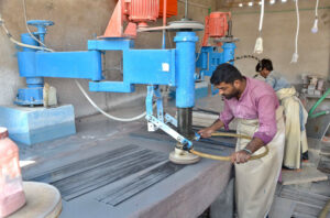 Labourers polishing marble slabs with machines at a marble industry