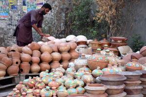 A vendor arranging and displaying the different kinds of clay pots to attract the customers at roadside setup